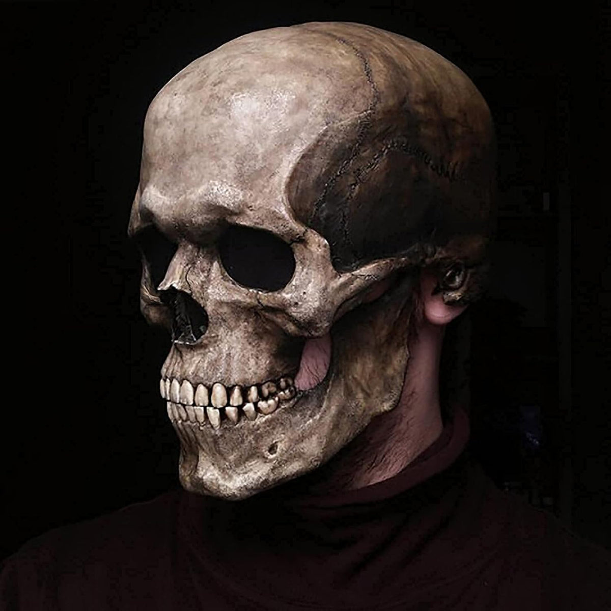 Skull mask worn by a person against a dark background