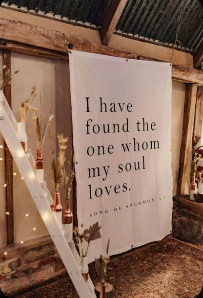 Decorative banner with a quote in a rustic setting with lights and plants.